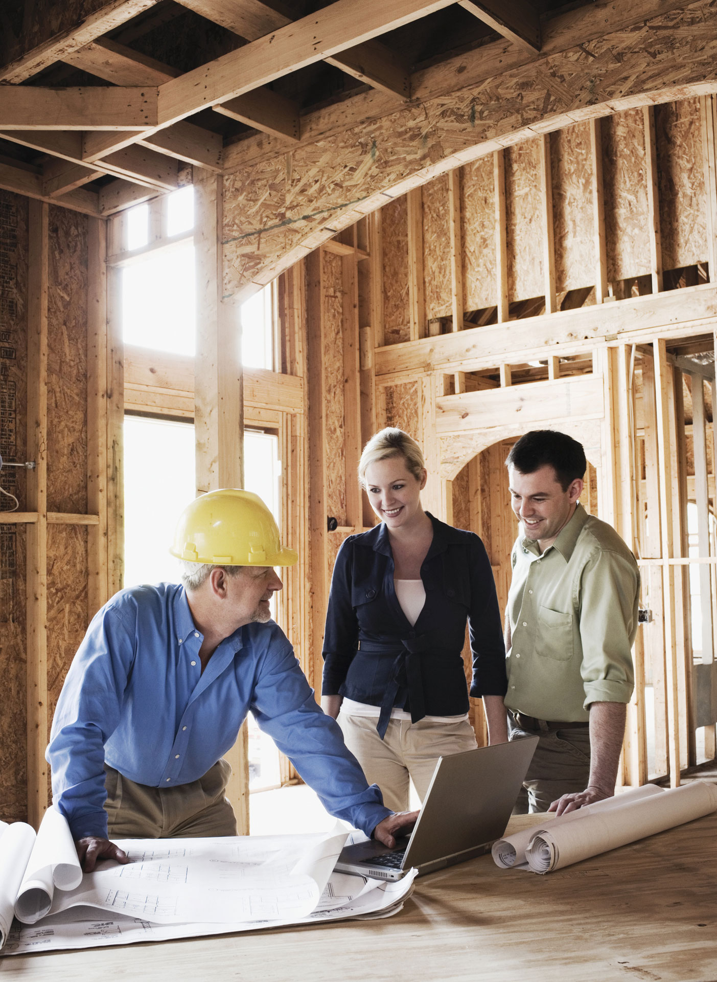 Builder with blueprints meeting others in new construction building